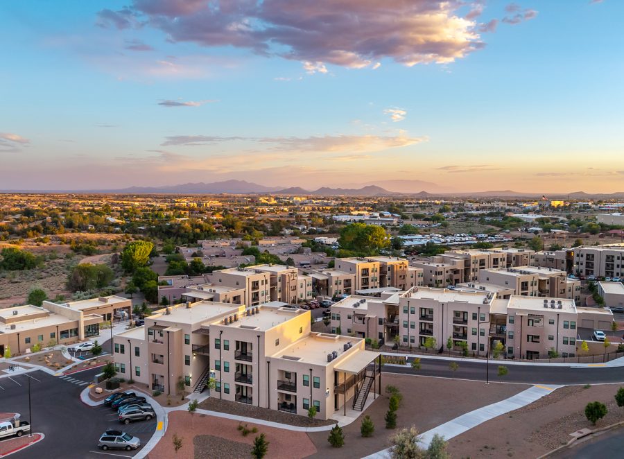 Aerial view of Turquesa Apartments in Santa Fe, New Mexico at dusk, showing multiple stucco walk-up buildings with desert landscaping and mountains in the distance.